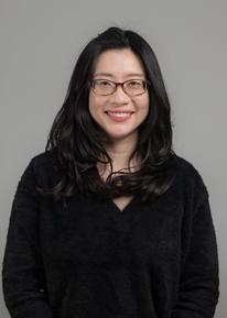 The image shows a woman wearing glasses with medium length dark hair.